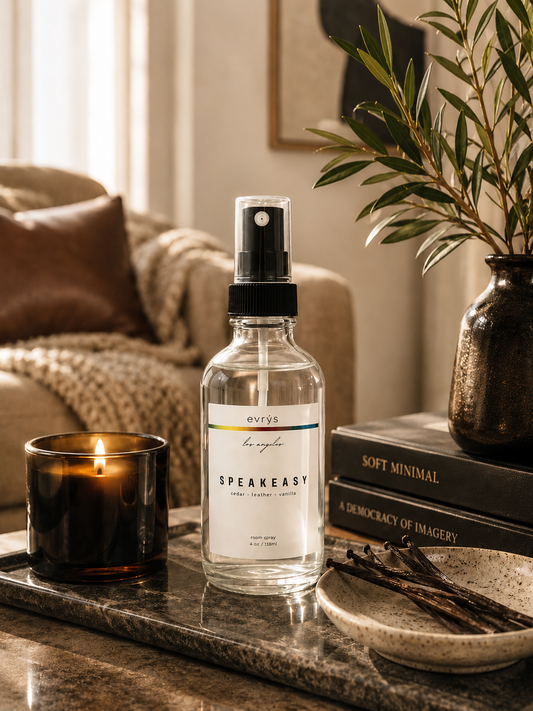 Speakeasy room spray bottle on a table with a candle and books in a cozy room.
