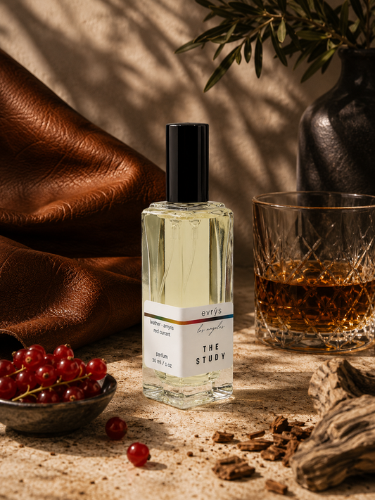 Perfume bottle labeled 'The Study' with a glass of whiskey, red currant, and leather texture in the background.