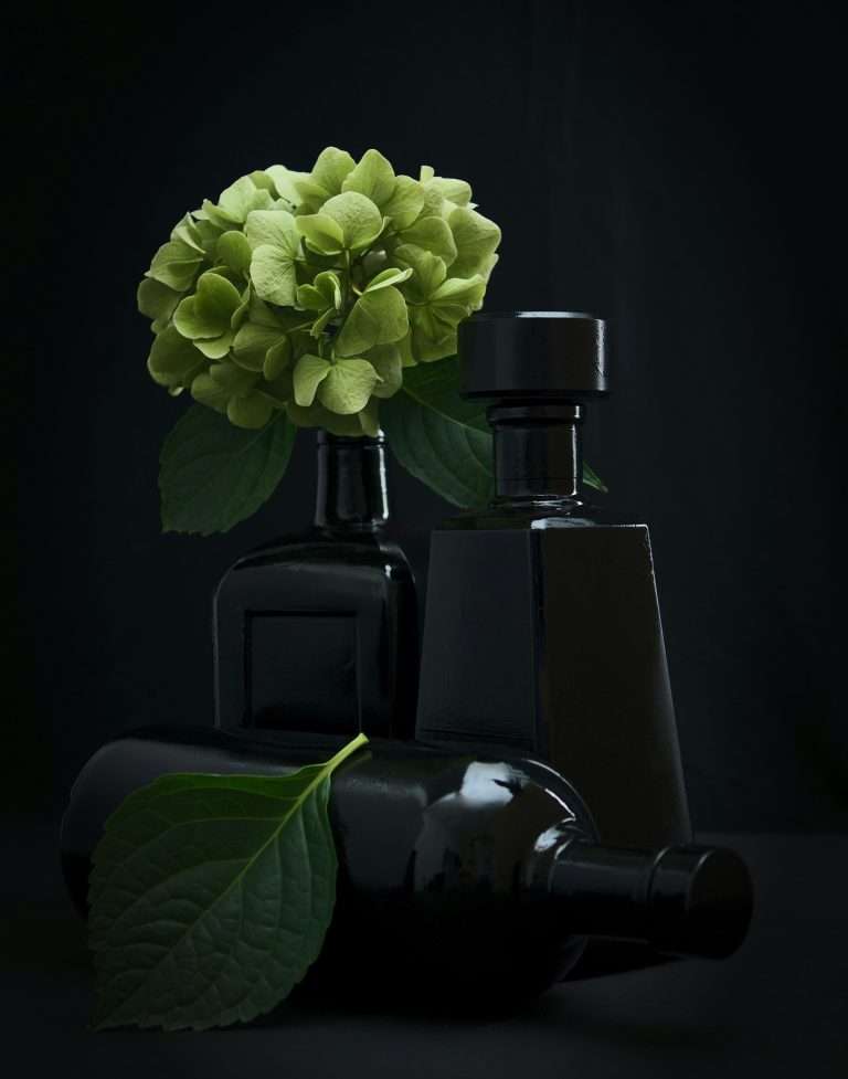 Black perfume bottles with green flowers on a dark background