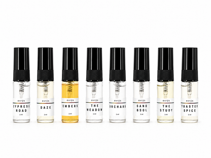Set of eight small perfume bottles with black caps on a white background