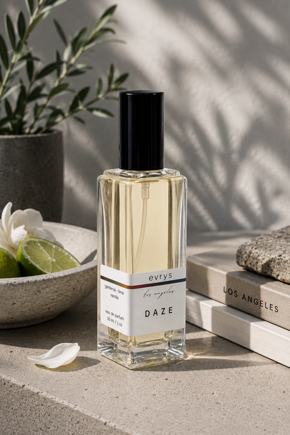Perfume bottle labeled 'evrys' Daze on a surface with a plant and books in the background