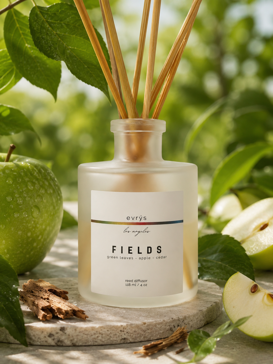 Reed diffuser labeled 'FIELDS' by evrys with green apples and leaves in the background