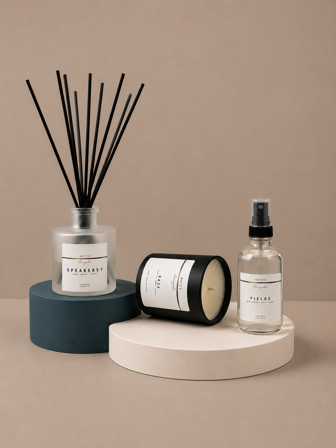 A diffuser, candle, and room spray bottle on a beige surface with a neutral background