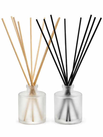 Two diffuser bottles with wooden and black reeds on a white background