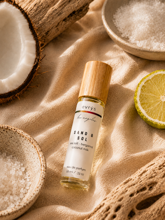 evrys oil roller bottle labeled 'Sand & Sol' on a textured surface with coconut and lime elements.