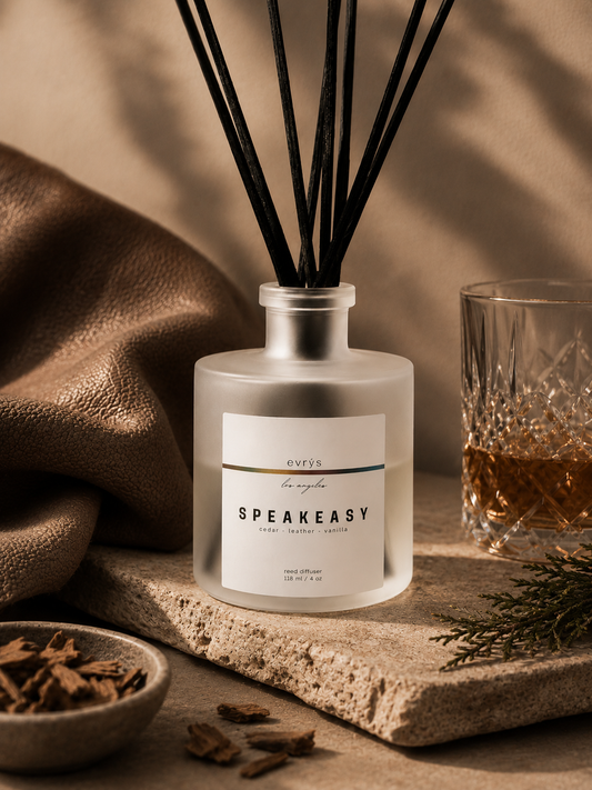 Speakeasy diffuser bottle with decorative elements of leather, spice, and whiskey on a wooden surface