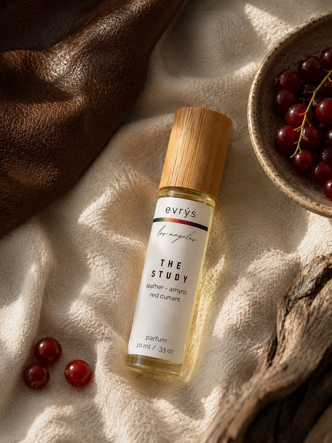evrys The Study oil roller bottle on a textured surface with grapes