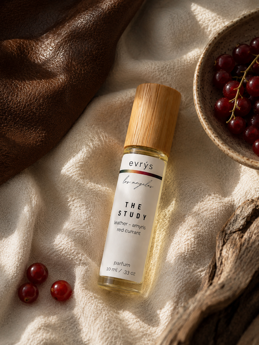 evrys The Study oil roller bottle on a textured surface with grapes