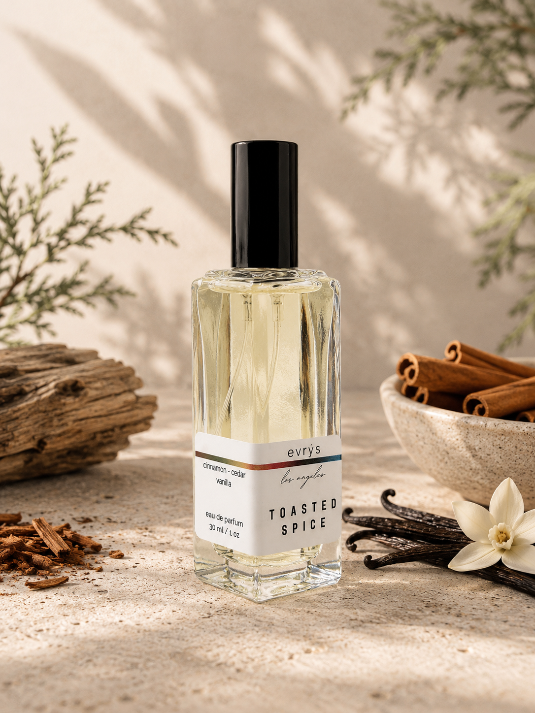 Perfume bottle labeled 'Toasted Spice' with cinnamon sticks and vanilla beans on a wooden surface.