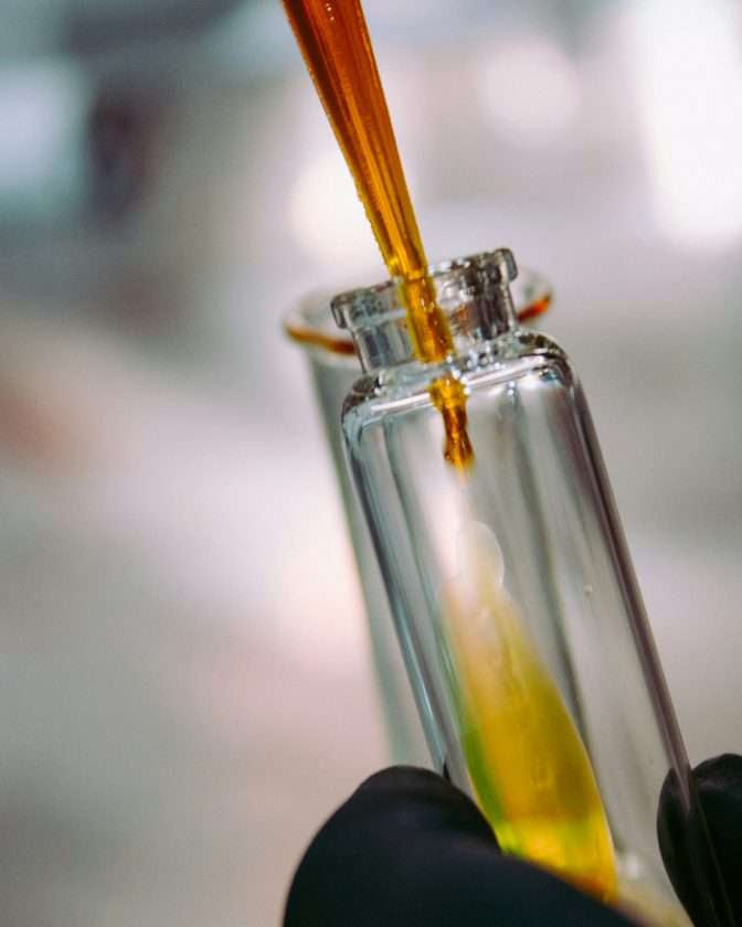Liquid being poured from a dropper into a test tube with a blurred background